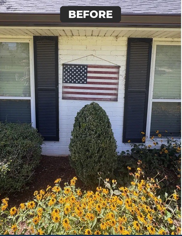 The front windows of a white brick house before cleaning