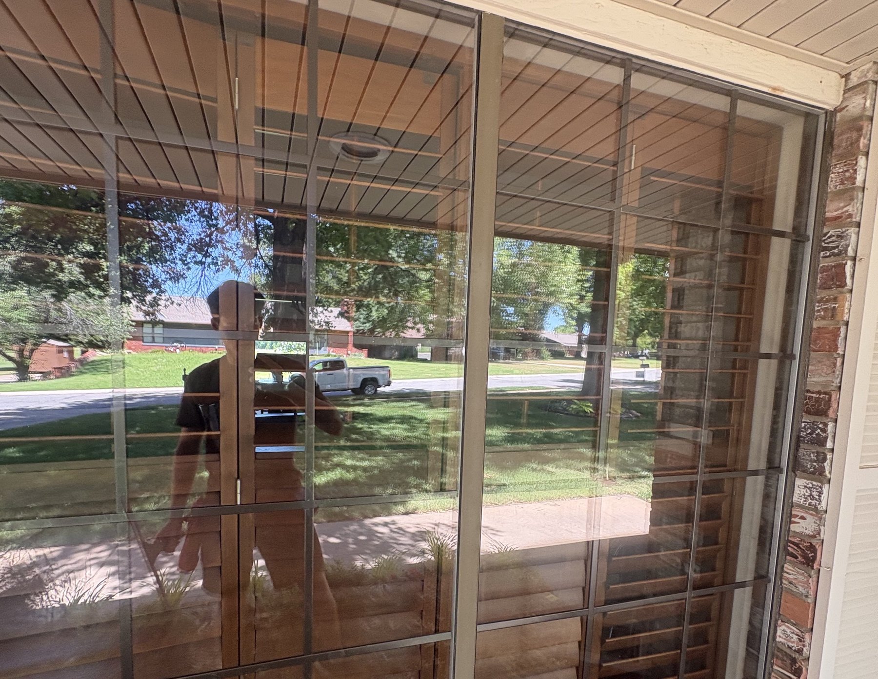 A wall of freshly cleaned patio glass reflecting the trees and street outside