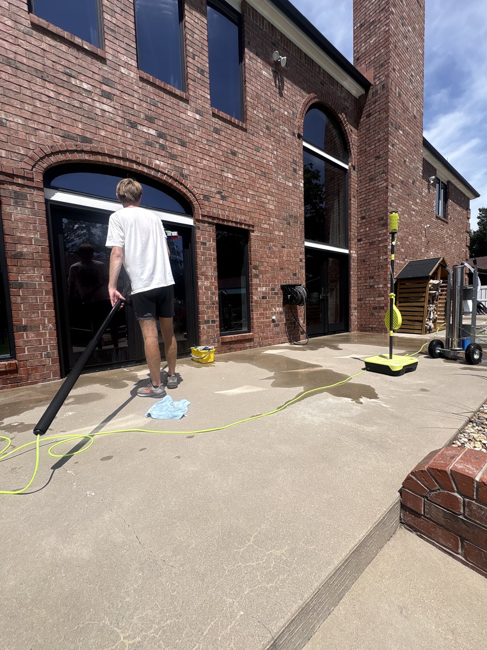 Cleaning the tall arched windows of a brick commercial building with a water-fed pole