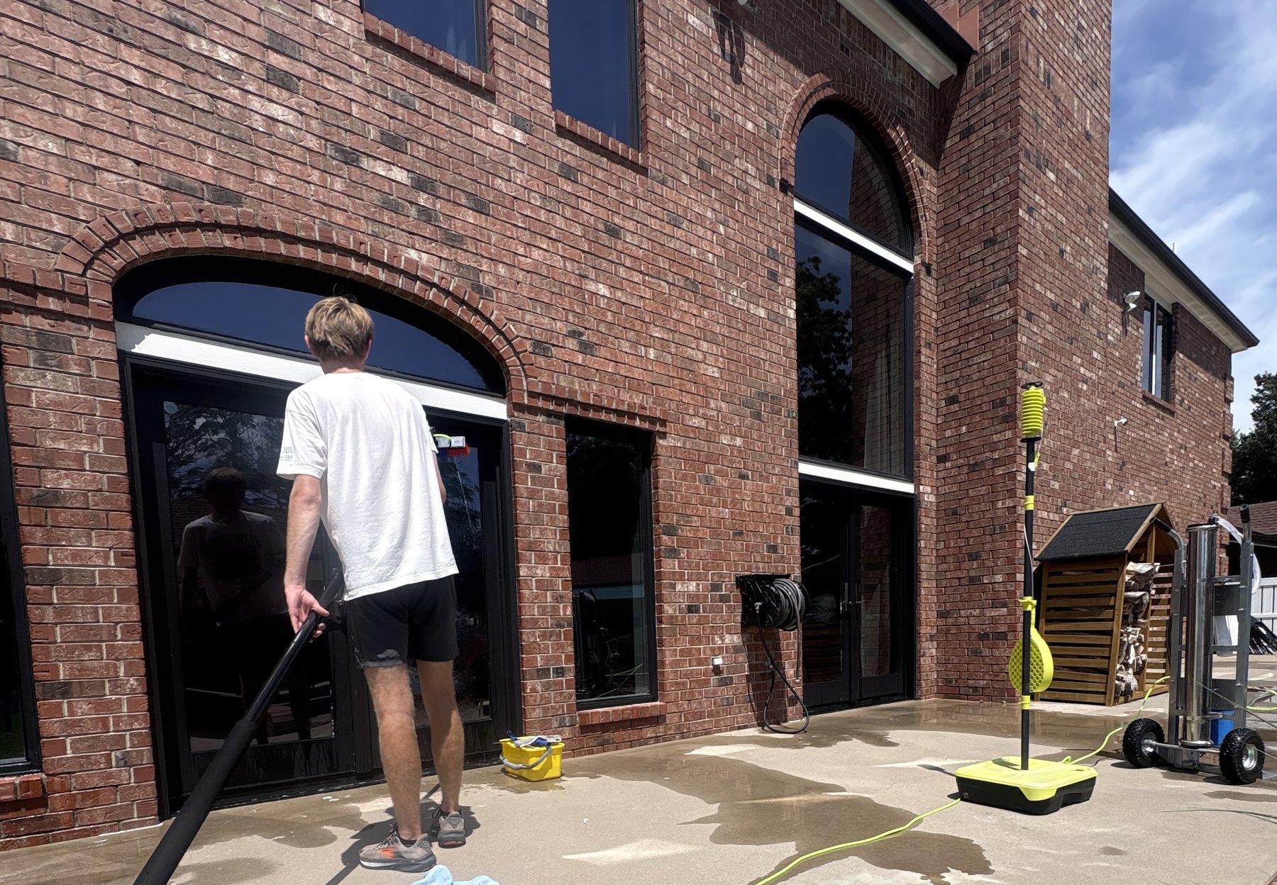 Working the tall arched windows of a brick commercial building with a water-fed pole